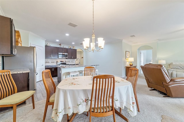 dining space with an inviting chandelier, crown molding, and sink