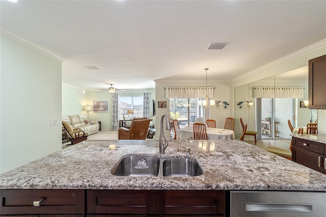 kitchen featuring a center island with sink, ceiling fan with notable chandelier, sink, dark brown cabinets, and light stone counters