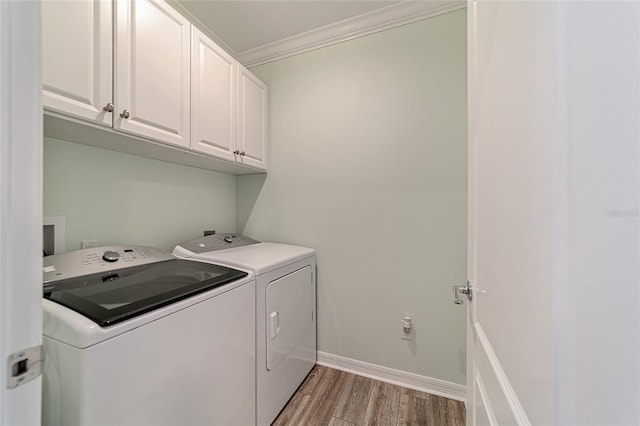 clothes washing area featuring washer and dryer, wood-type flooring, cabinets, and ornamental molding