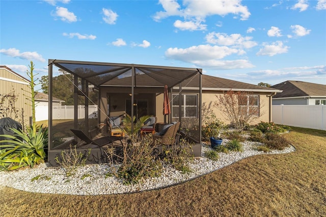 back of house featuring glass enclosure and a yard