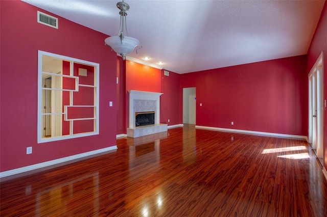 unfurnished living room featuring hardwood / wood-style flooring, a premium fireplace, and a textured ceiling