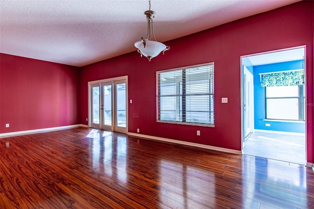 empty room featuring a wealth of natural light, french doors, a textured ceiling, and hardwood / wood-style flooring