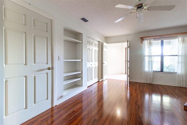 unfurnished bedroom featuring ceiling fan, dark hardwood / wood-style floors, and a textured ceiling