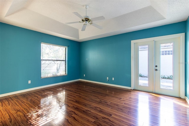 spare room featuring a tray ceiling, ceiling fan, french doors, and dark hardwood / wood-style floors