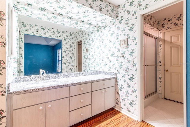 bathroom featuring vanity, wood-type flooring, and a shower with door