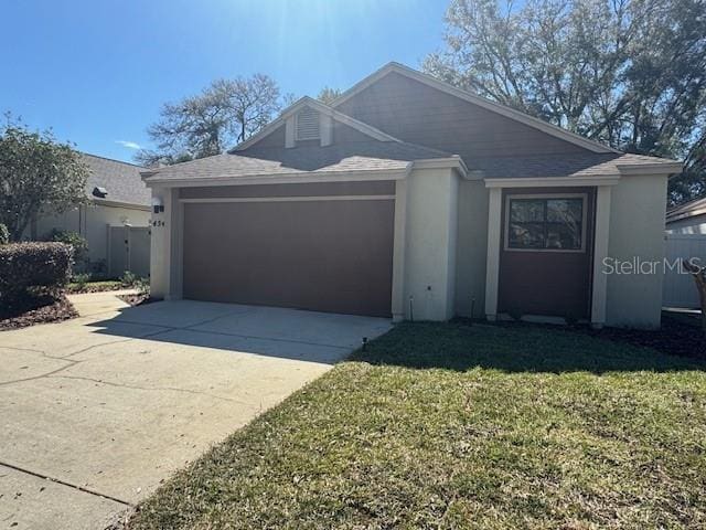 ranch-style house featuring an attached garage, a front yard, concrete driveway, and stucco siding