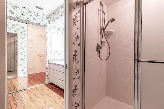 full bath with a stall shower, wood finished floors, and wallpapered walls