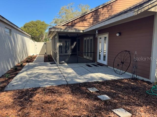 exterior space featuring a patio, a gate, fence, french doors, and a sunroom