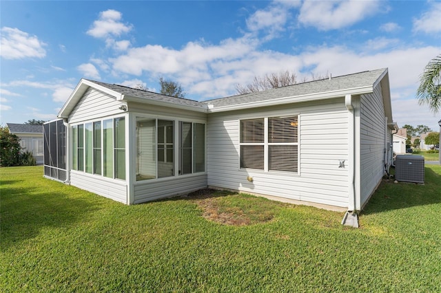 rear view of house featuring central AC unit, a sunroom, and a yard