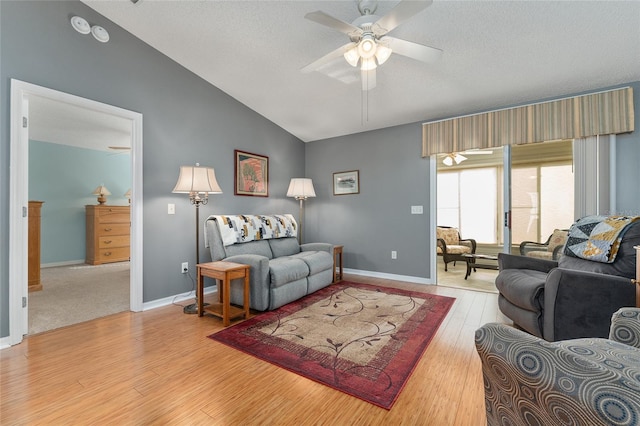 living room with a textured ceiling, light wood-type flooring, ceiling fan, and lofted ceiling