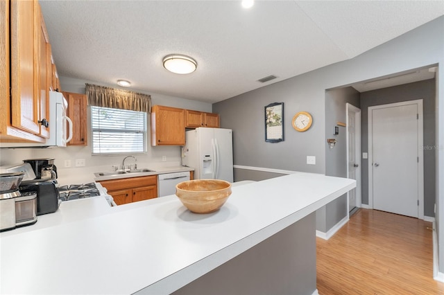 kitchen with kitchen peninsula, a textured ceiling, white appliances, and sink