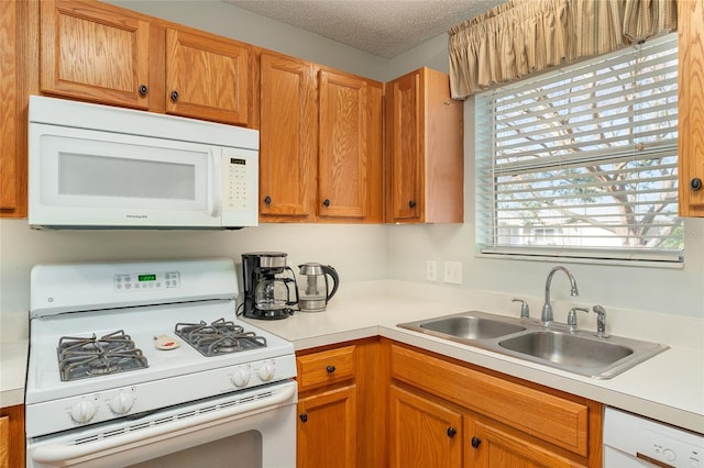 kitchen with a textured ceiling, sink, and white appliances