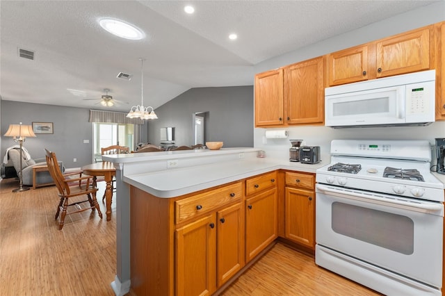 kitchen featuring a textured ceiling, lofted ceiling, white appliances, and kitchen peninsula