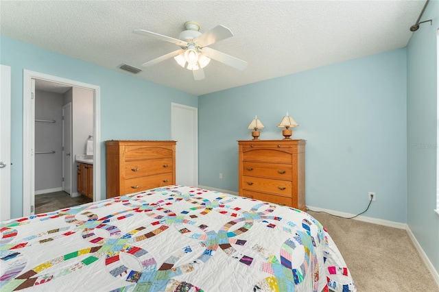 carpeted bedroom with ceiling fan, a textured ceiling, and ensuite bath