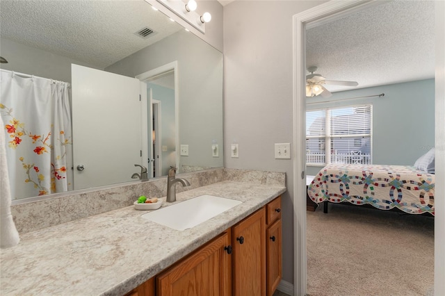 bathroom with ceiling fan, vanity, and a textured ceiling