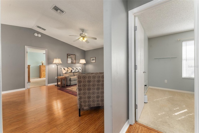 interior space with a textured ceiling, light hardwood / wood-style floors, and lofted ceiling