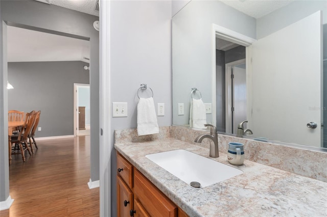 bathroom with hardwood / wood-style flooring, vanity, and a textured ceiling