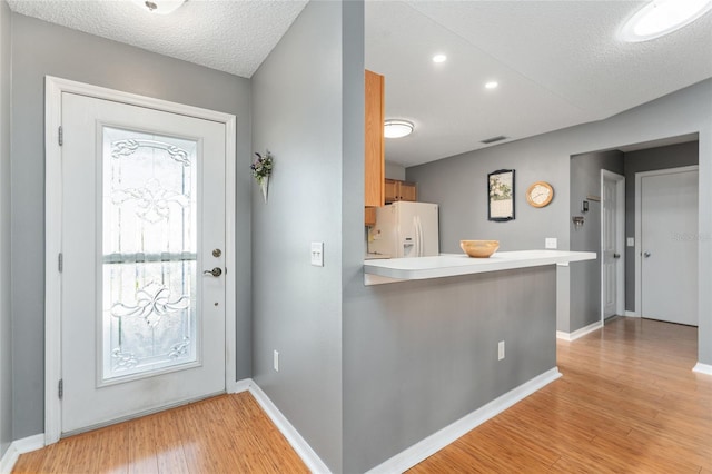 entryway with a textured ceiling and light hardwood / wood-style floors