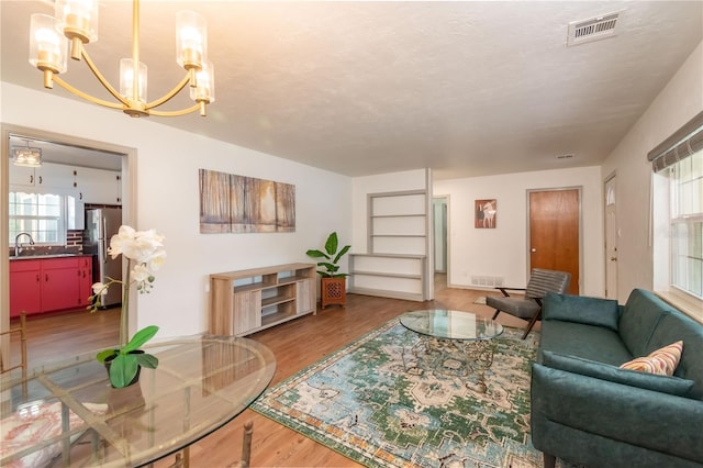 living room with sink, hardwood / wood-style floors, a textured ceiling, and a notable chandelier