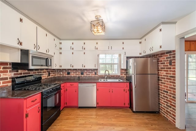 kitchen with white cabinets, sink, stainless steel appliances, and brick wall