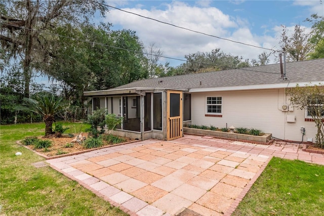 rear view of property featuring a yard, a patio, and a sunroom