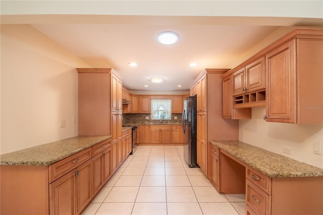 kitchen with light stone countertops, built in desk, stainless steel appliances, and kitchen peninsula