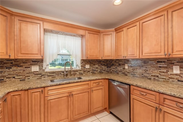 kitchen with light tile patterned floors, light stone counters, stainless steel dishwasher, and sink