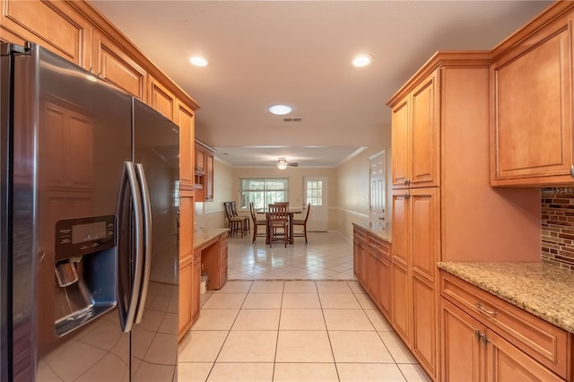 kitchen with crown molding, decorative backsplash, stainless steel fridge, light stone countertops, and light tile patterned flooring