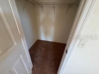 spacious closet featuring dark colored carpet