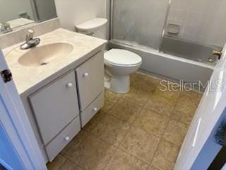 full bathroom featuring vanity, combined bath / shower with glass door, and toilet