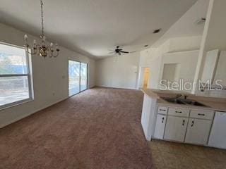 unfurnished living room featuring carpet flooring and ceiling fan with notable chandelier