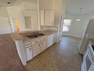 kitchen featuring white cabinetry, sink, hanging light fixtures, stove, and white dishwasher