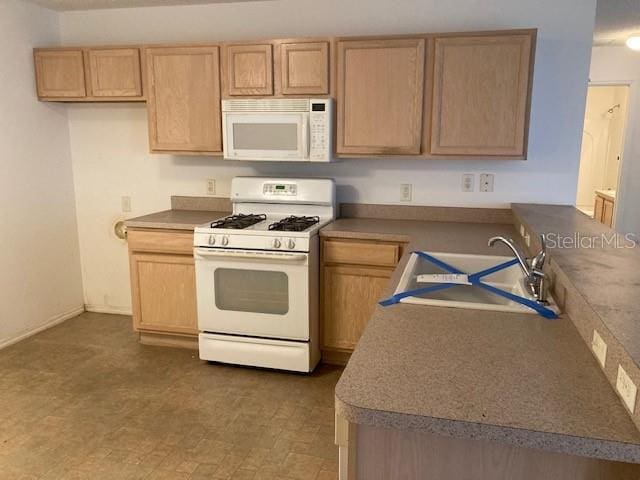 kitchen featuring sink, light brown cabinetry, and white appliances