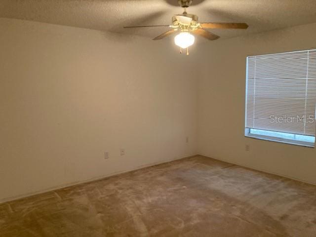 carpeted empty room with ceiling fan and a textured ceiling