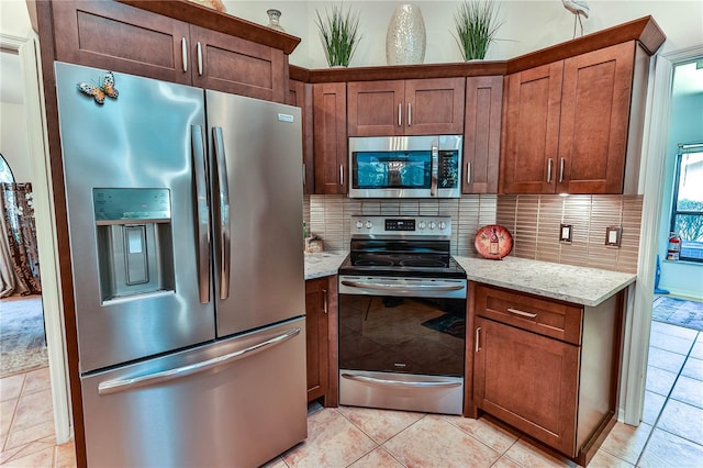 kitchen featuring tasteful backsplash, light tile patterned floors, light stone countertops, and appliances with stainless steel finishes