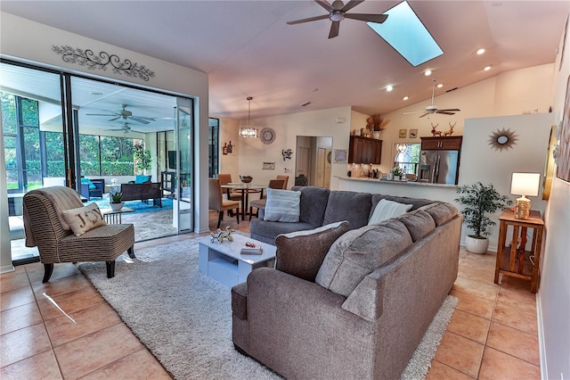 tiled living room with ceiling fan and vaulted ceiling with skylight