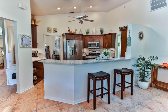 kitchen with ceiling fan, backsplash, stainless steel appliances, light tile patterned flooring, and kitchen peninsula