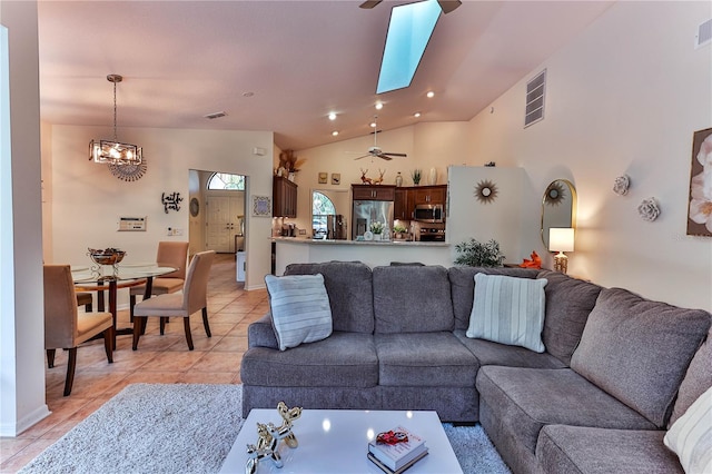 living room with ceiling fan with notable chandelier, light tile patterned floors, and high vaulted ceiling