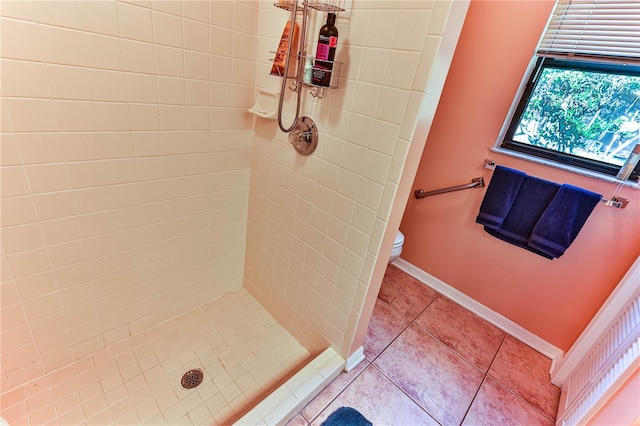 bathroom featuring tile patterned floors, toilet, and a tile shower