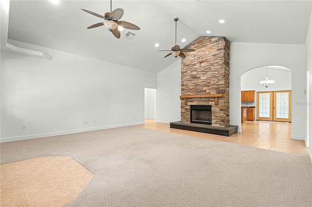 unfurnished living room with a fireplace, light tile patterned flooring, ceiling fan with notable chandelier, and high vaulted ceiling