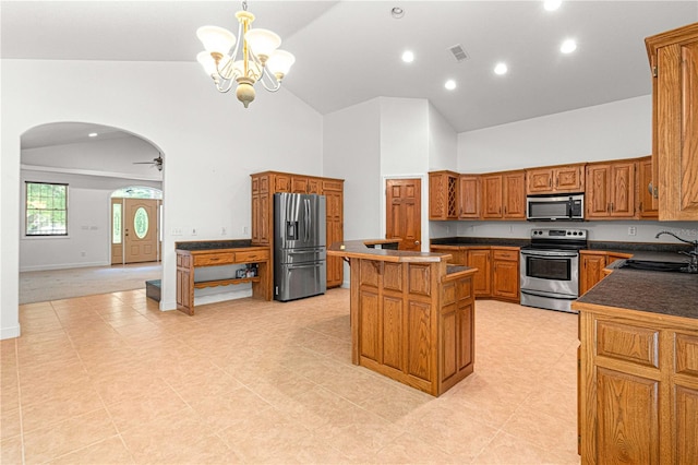 kitchen featuring sink, hanging light fixtures, a kitchen island, ceiling fan with notable chandelier, and appliances with stainless steel finishes