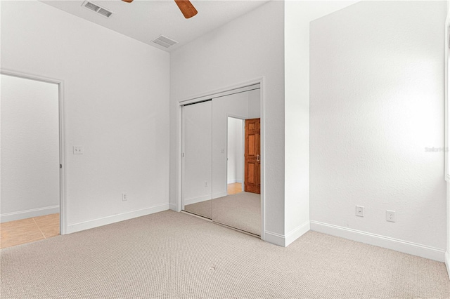 unfurnished bedroom with ceiling fan, light carpet, and a closet