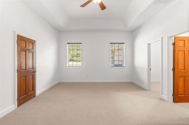 unfurnished bedroom with a tray ceiling, ceiling fan, and light colored carpet