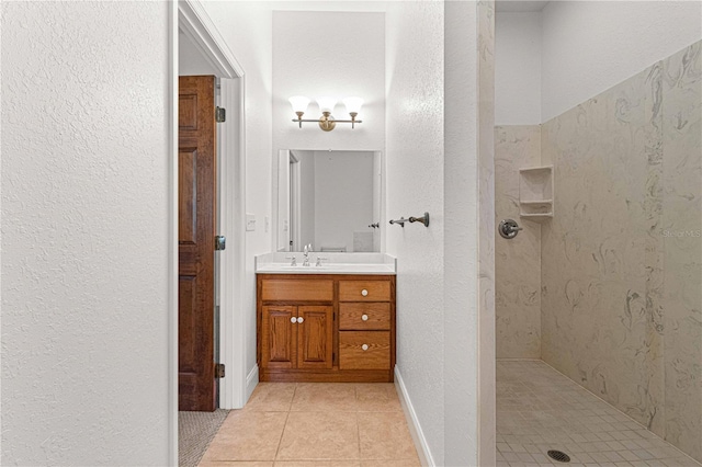 bathroom with tile patterned flooring, vanity, and tiled shower