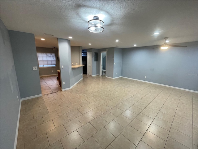 spare room featuring ceiling fan, light tile patterned floors, and a textured ceiling