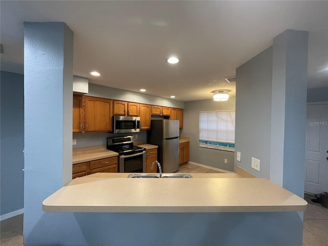 kitchen featuring kitchen peninsula, stainless steel appliances, light tile patterned flooring, and sink