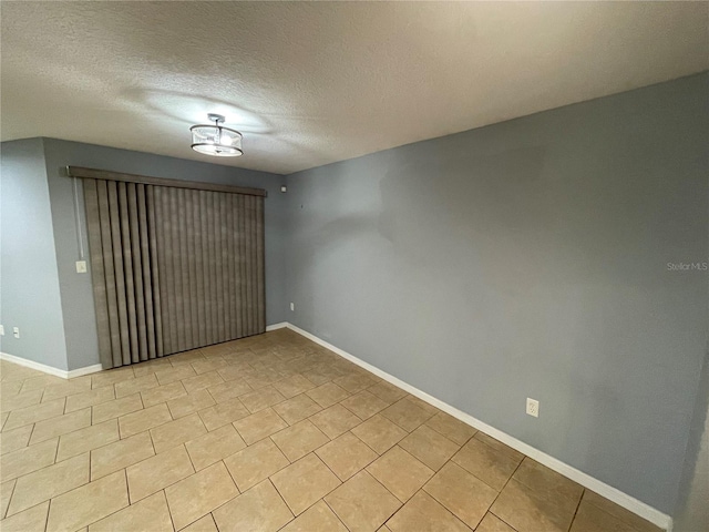 empty room featuring light tile patterned flooring and a textured ceiling