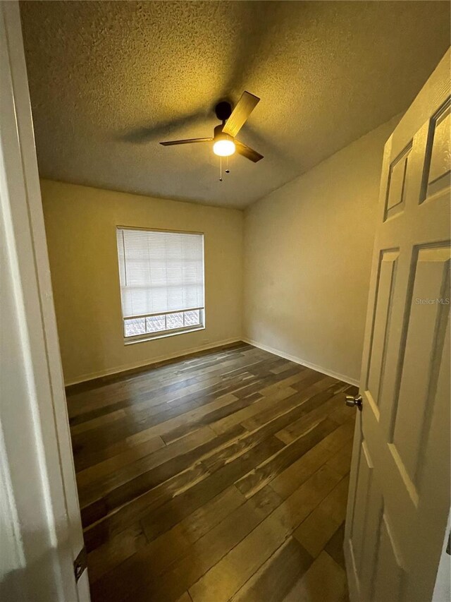 empty room with a textured ceiling, ceiling fan, and dark wood-type flooring