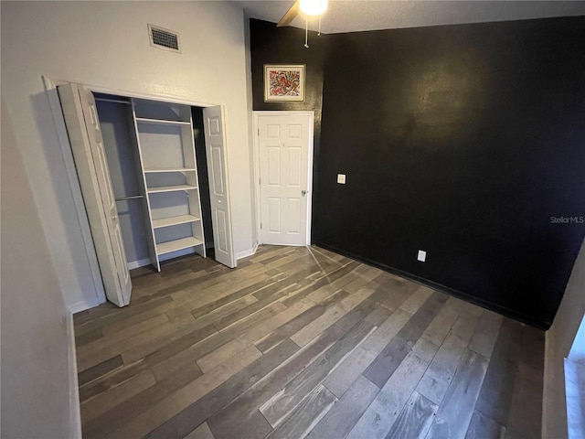 unfurnished bedroom featuring dark hardwood / wood-style flooring, a closet, and vaulted ceiling