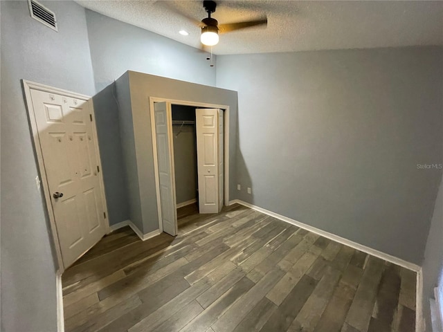 unfurnished bedroom with ceiling fan, dark hardwood / wood-style floors, a textured ceiling, and a closet